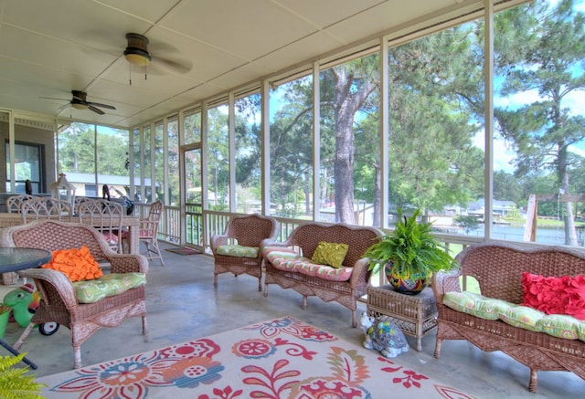 sunroom featuring ceiling fan, a water view, and a healthy amount of sunlight