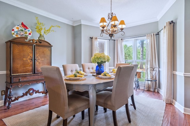 dining space featuring hardwood / wood-style floors, ornamental molding, and a notable chandelier