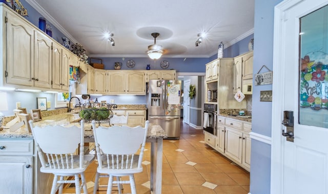 kitchen featuring appliances with stainless steel finishes, light tile patterned floors, a breakfast bar, ceiling fan, and light stone counters