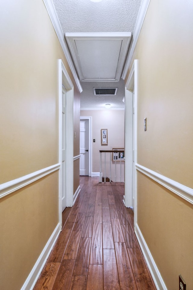 corridor featuring a textured ceiling, dark hardwood / wood-style floors, and ornamental molding