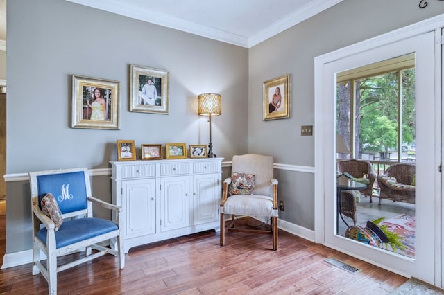 sitting room with crown molding and light wood-type flooring