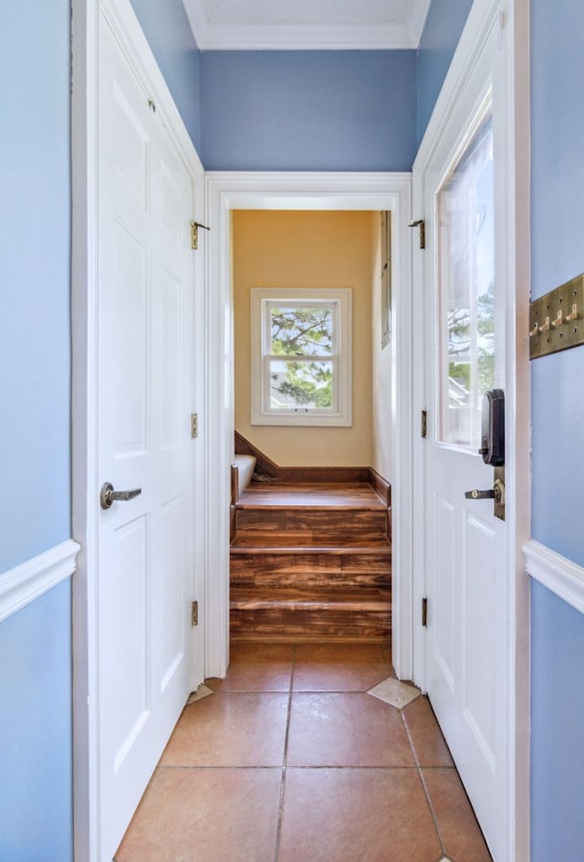 corridor featuring light tile patterned floors and crown molding