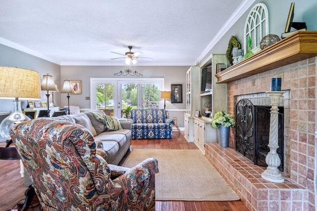 living room with a textured ceiling, a fireplace, ceiling fan, hardwood / wood-style flooring, and crown molding