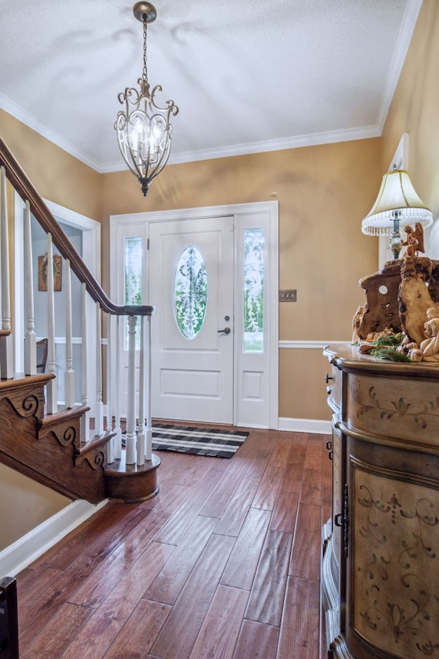 entrance foyer with a chandelier, crown molding, and wood-type flooring