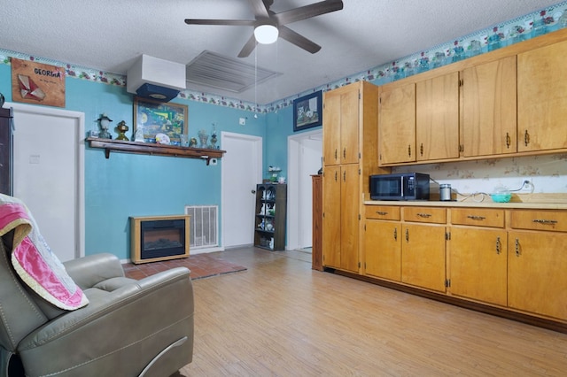 272 Ellis Rd, Plains, GA 31780 - living area with a ceiling fan, a textured ceiling, visible vents, a glass covered fireplace, and light wood-style floors