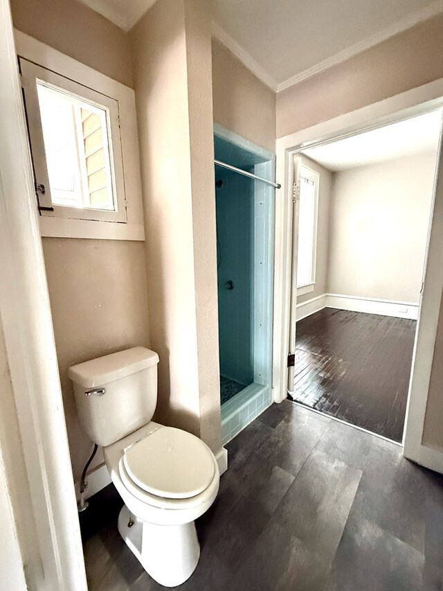 bathroom featuring crown molding, toilet, a tile shower, and a healthy amount of sunlight