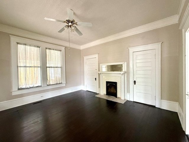 unfurnished living room with crown molding, ceiling fan, dark wood-type flooring, a brick fireplace, and a textured ceiling