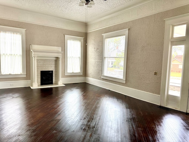 unfurnished living room with a textured ceiling, dark wood-type flooring, ceiling fan, ornamental molding, and a brick fireplace