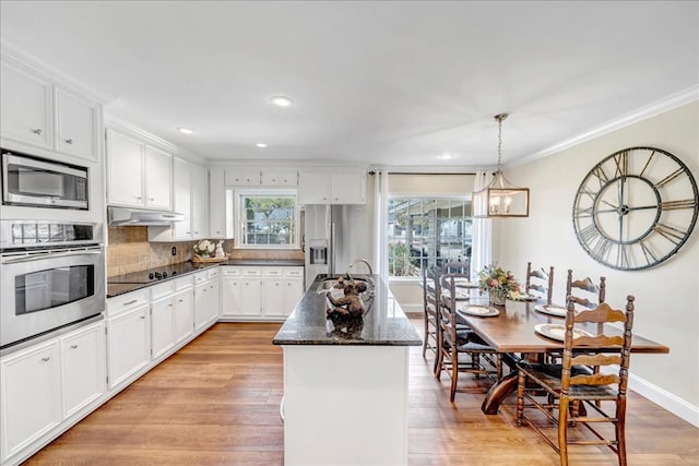 kitchen featuring light hardwood / wood-style floors, appliances with stainless steel finishes, white cabinets, a kitchen island, and decorative light fixtures