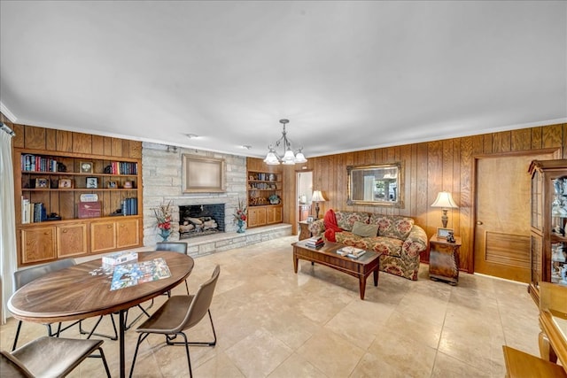 living room with built in shelves, wooden walls, a fireplace, and ornamental molding