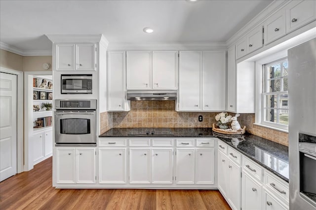 kitchen featuring white cabinets, stainless steel appliances, and dark stone counters