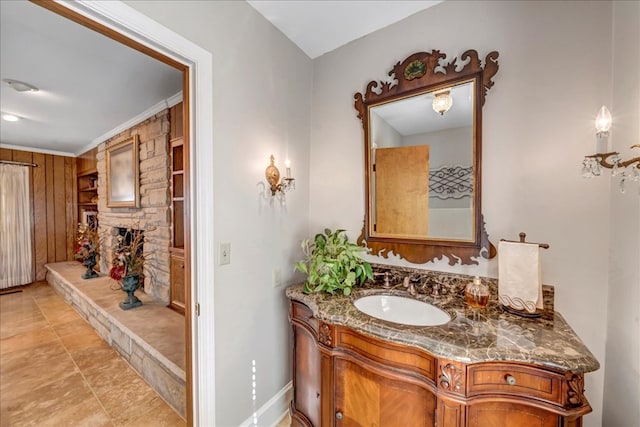 bathroom with a fireplace, crown molding, wooden walls, and vanity