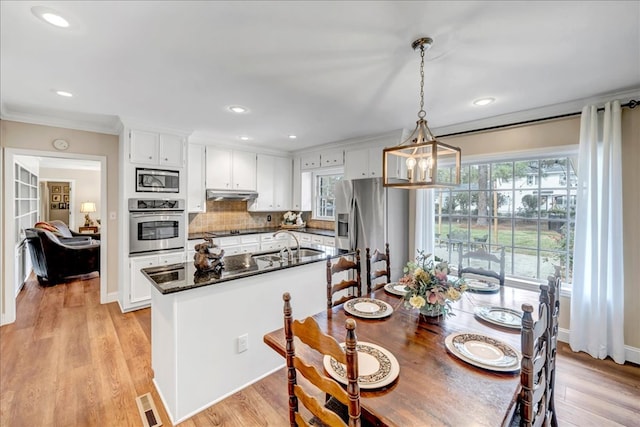 dining room with sink, light hardwood / wood-style floors, a chandelier, and ornamental molding