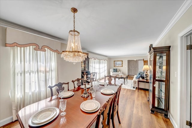 dining room with light wood-type flooring, crown molding, and a notable chandelier