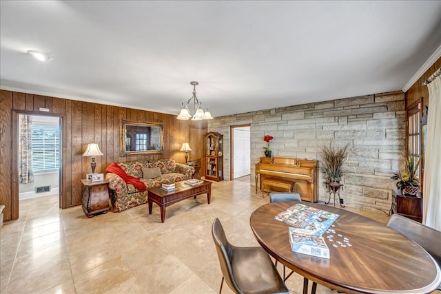 dining room with wood walls, a chandelier, and ornamental molding