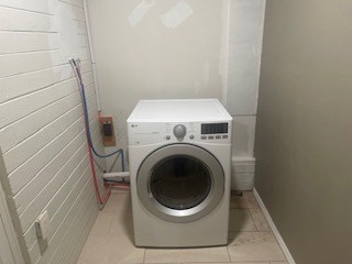 laundry room with washer / clothes dryer and light tile patterned flooring