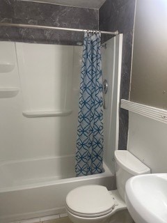 bathroom featuring toilet, shower / bath combo, and tile patterned flooring