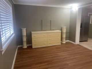 unfurnished bedroom with ornamental molding, dark hardwood / wood-style floors, and stainless steel fridge