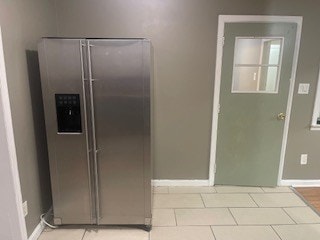 kitchen featuring stainless steel fridge with ice dispenser and light tile patterned flooring