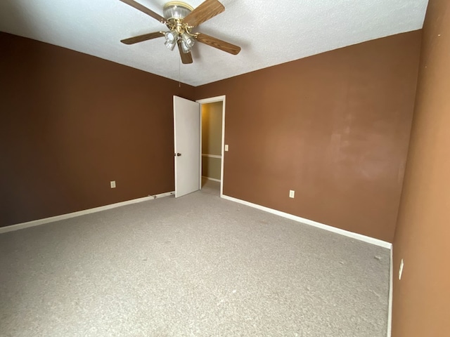 unfurnished room with a textured ceiling, ceiling fan, and carpet