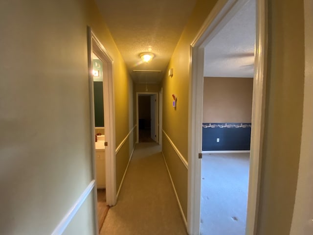 corridor featuring light carpet and a textured ceiling