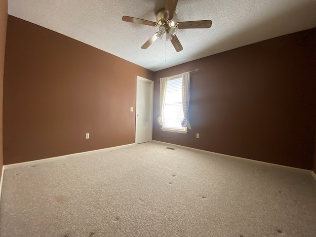 carpeted spare room with ceiling fan and a textured ceiling