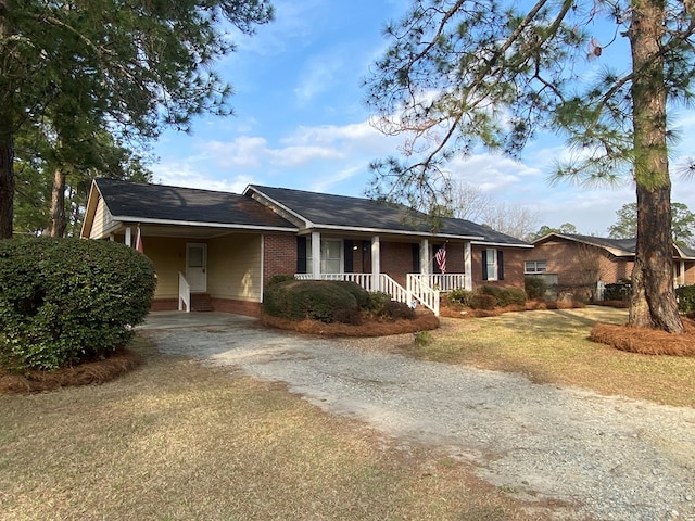 ranch-style home with a carport, a front yard, and covered porch