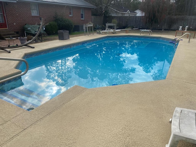 view of pool with a patio and a diving board