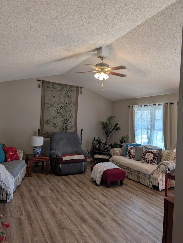 living room featuring vaulted ceiling, wood-type flooring, ceiling fan, and a textured ceiling