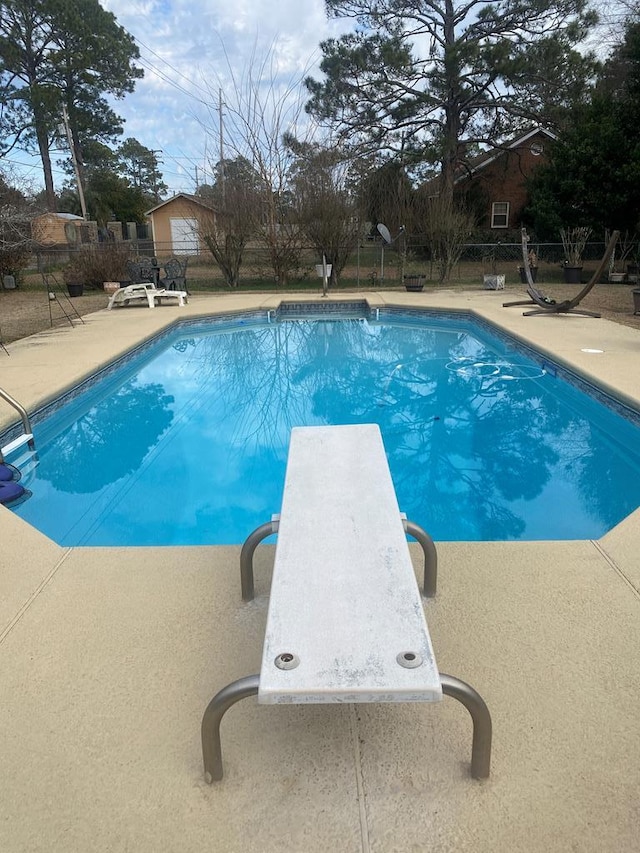 view of swimming pool with a diving board and a patio