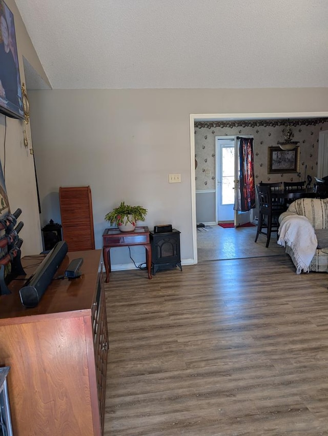 bedroom with wood-type flooring, a textured ceiling, and a wood stove