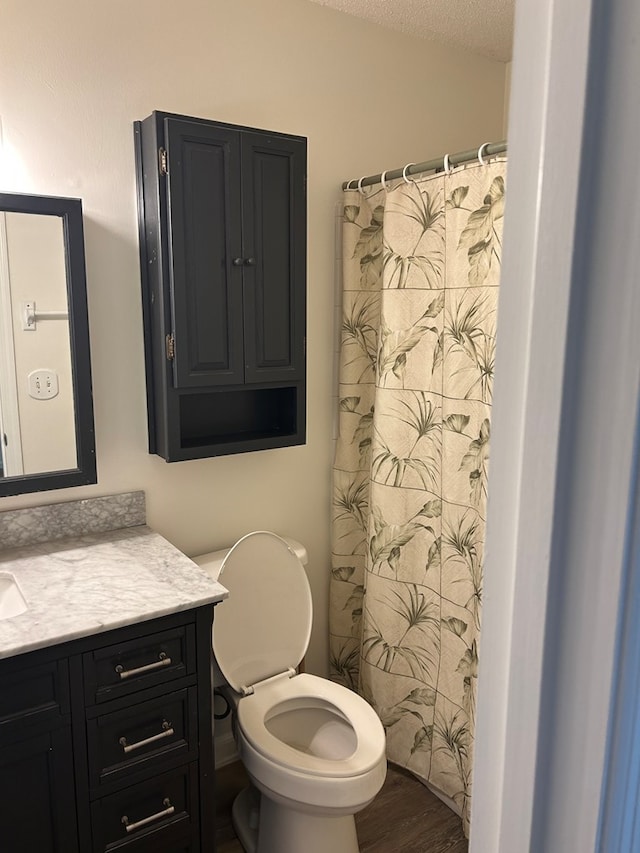 full bathroom with toilet, a shower with curtain, wood finished floors, a textured ceiling, and vanity