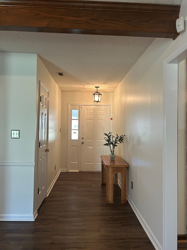 entrance foyer featuring a textured ceiling, dark wood-style flooring, and visible vents