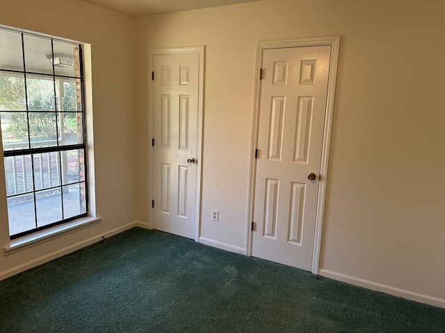 unfurnished bedroom with dark carpet and baseboards