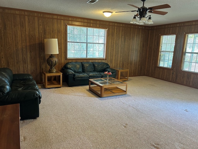 living room with visible vents, ornamental molding, a textured ceiling, carpet floors, and wood walls