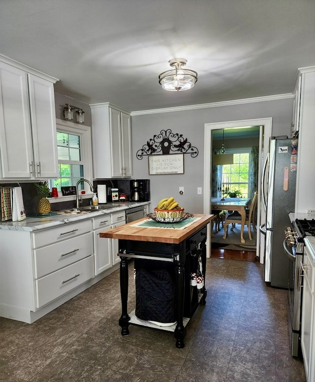 kitchen with white cabinets, wooden counters, appliances with stainless steel finishes, and a sink