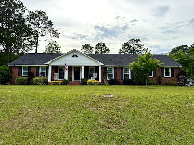 view of front of house with brick siding, a front lawn, and covered porch