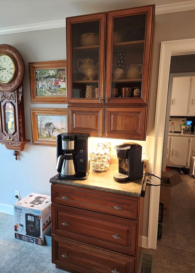 room details featuring light countertops, visible vents, crown molding, and glass insert cabinets