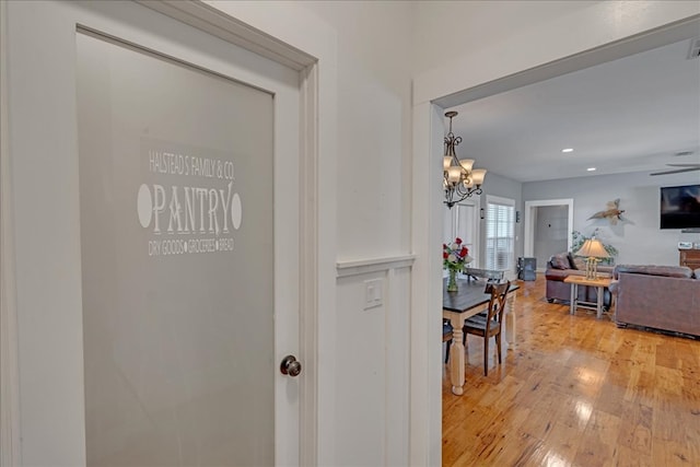 corridor featuring an inviting chandelier and light hardwood / wood-style flooring