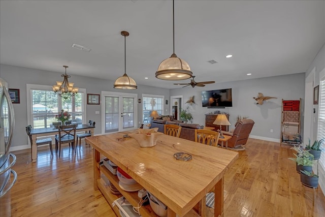 dining room with ceiling fan with notable chandelier and light wood-type flooring