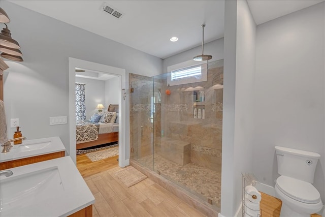 bathroom featuring hardwood / wood-style flooring, tiled shower, vanity, and toilet