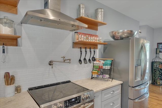 kitchen with light stone counters, white cabinetry, light hardwood / wood-style flooring, appliances with stainless steel finishes, and wall chimney range hood