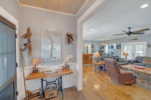 interior space with ornamental molding, ceiling fan with notable chandelier, and light hardwood / wood-style flooring