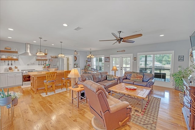 living room featuring french doors, ceiling fan with notable chandelier, and light wood-type flooring