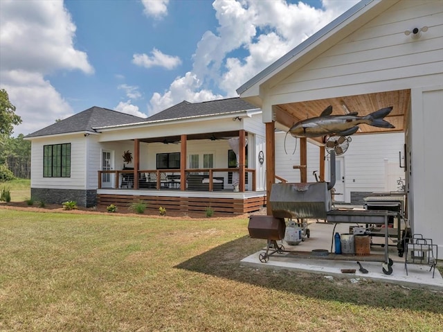 rear view of property with ceiling fan, a yard, and a patio