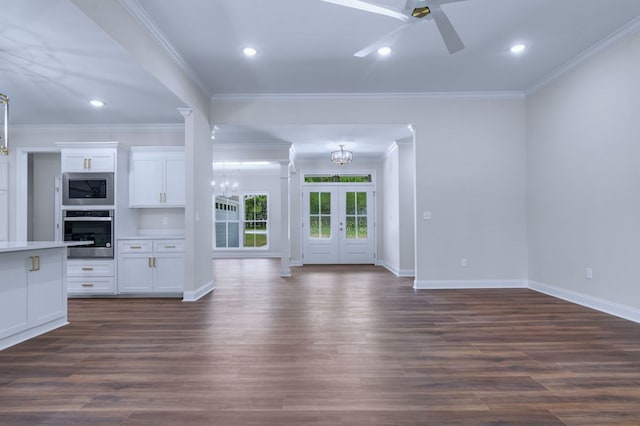 unfurnished living room featuring crown molding, ceiling fan with notable chandelier, dark wood-type flooring, and french doors