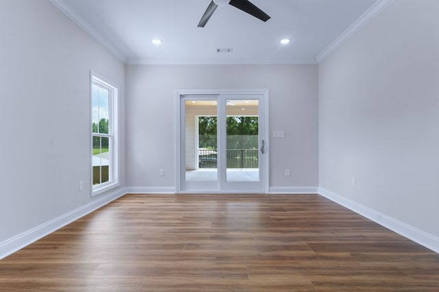 empty room with dark hardwood / wood-style flooring, crown molding, and a healthy amount of sunlight