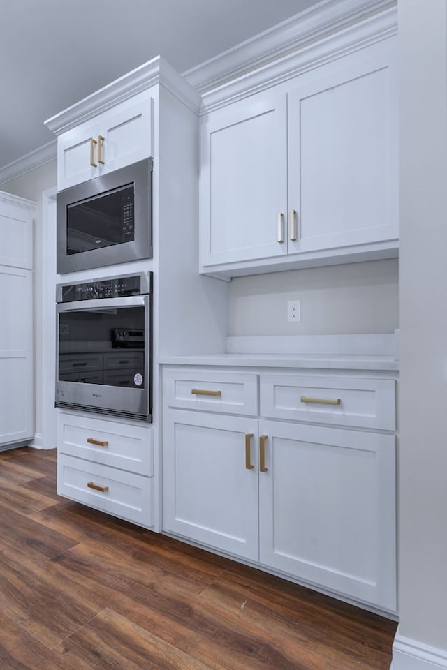 kitchen with dark hardwood / wood-style floors, built in microwave, white cabinets, oven, and ornamental molding