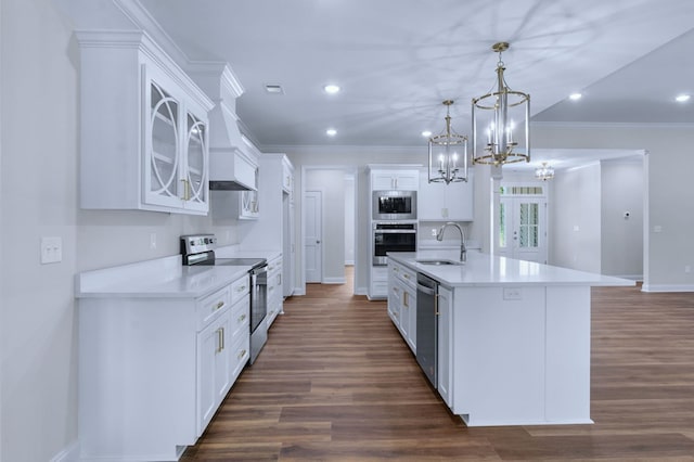 kitchen with appliances with stainless steel finishes, pendant lighting, sink, white cabinets, and a center island with sink