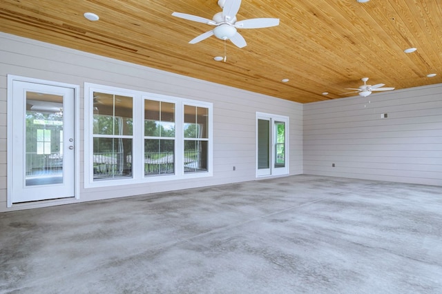 exterior space featuring wood ceiling, ceiling fan, wooden walls, and concrete floors